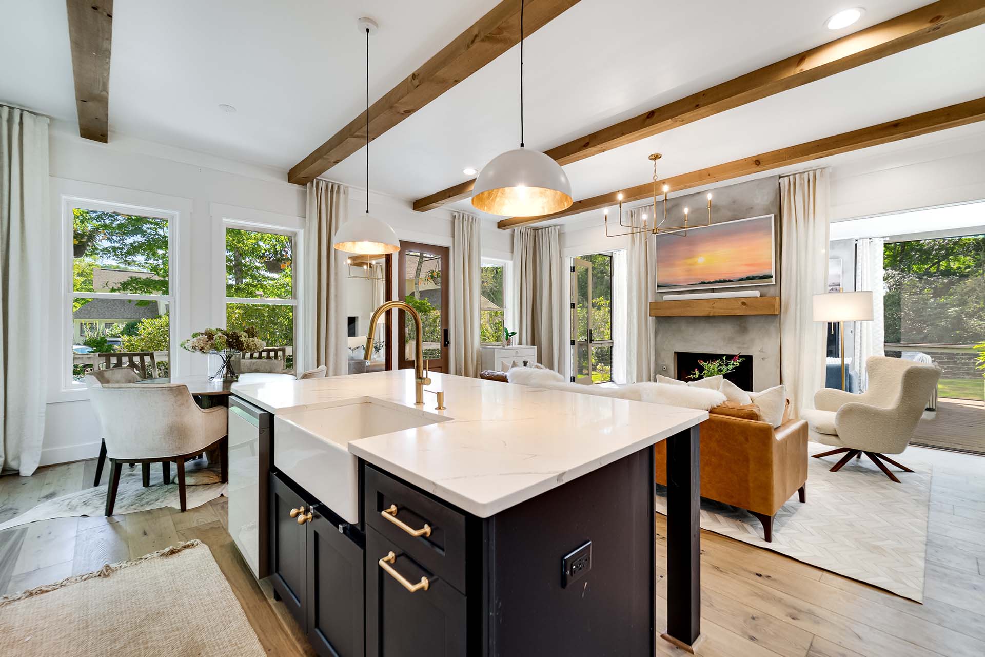 Modern kitchen with marble island, gold fixtures, and open living area with large windows and cozy seating—perfect for a stylish modular home.